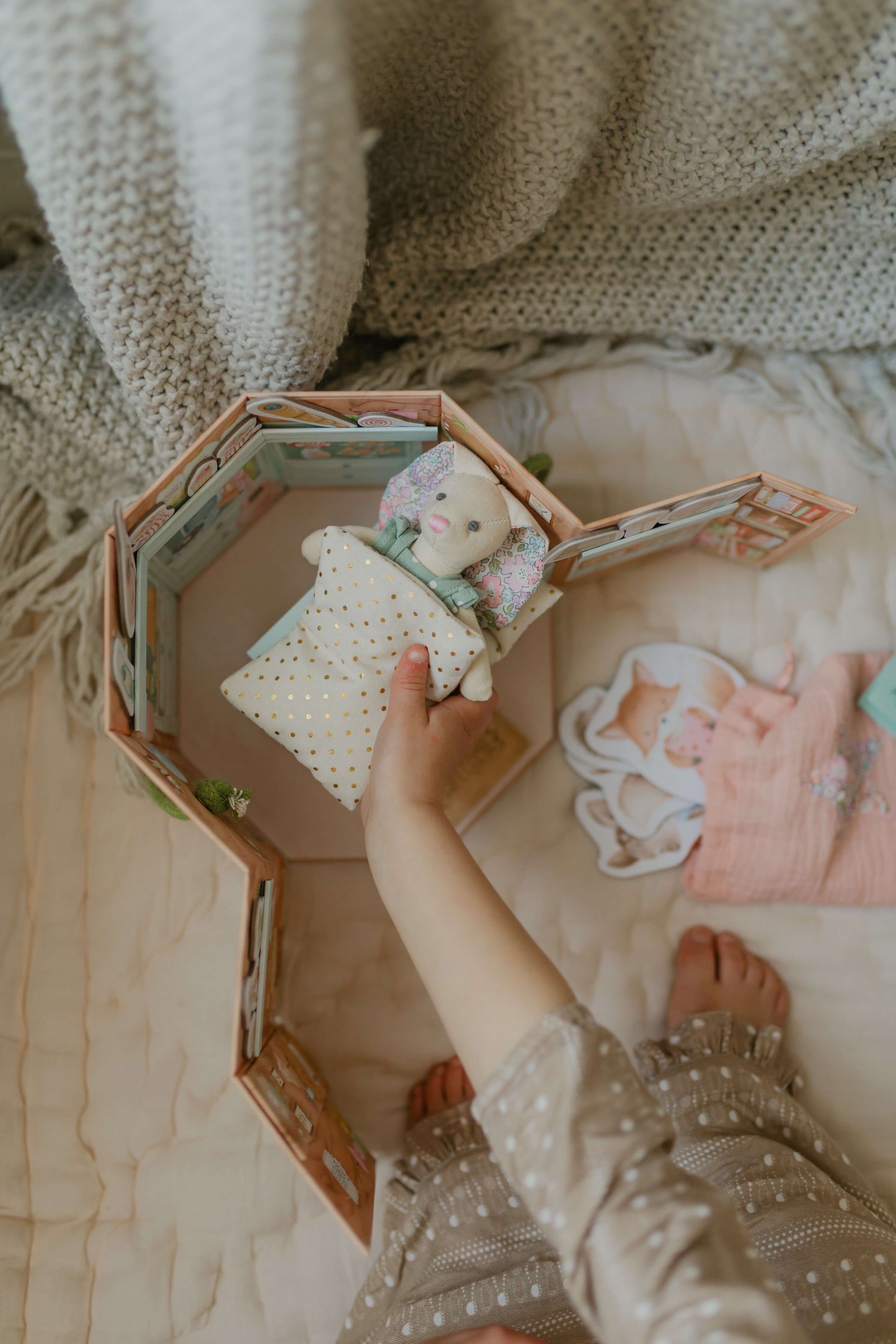 Child's hand playing with the Woodland Wonders children's playset. Putting Betsy Bunny to bed.