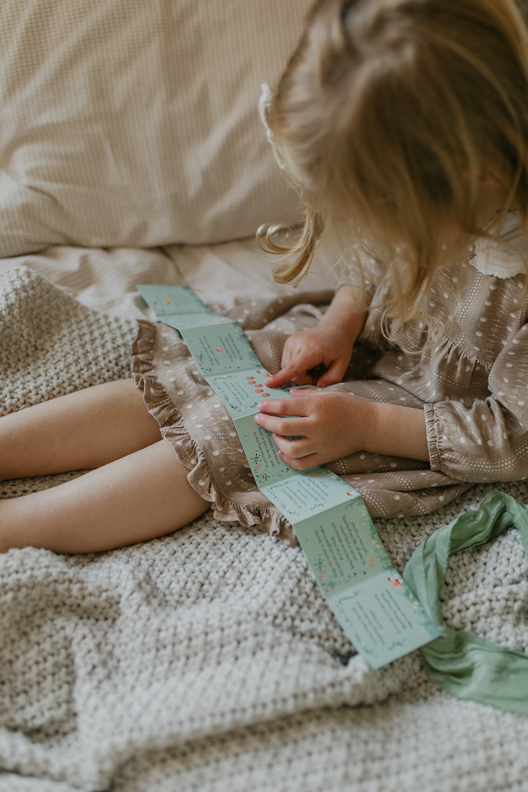Child sitting on a bed reading the little storybook from the Woodland Wonders children's playset.