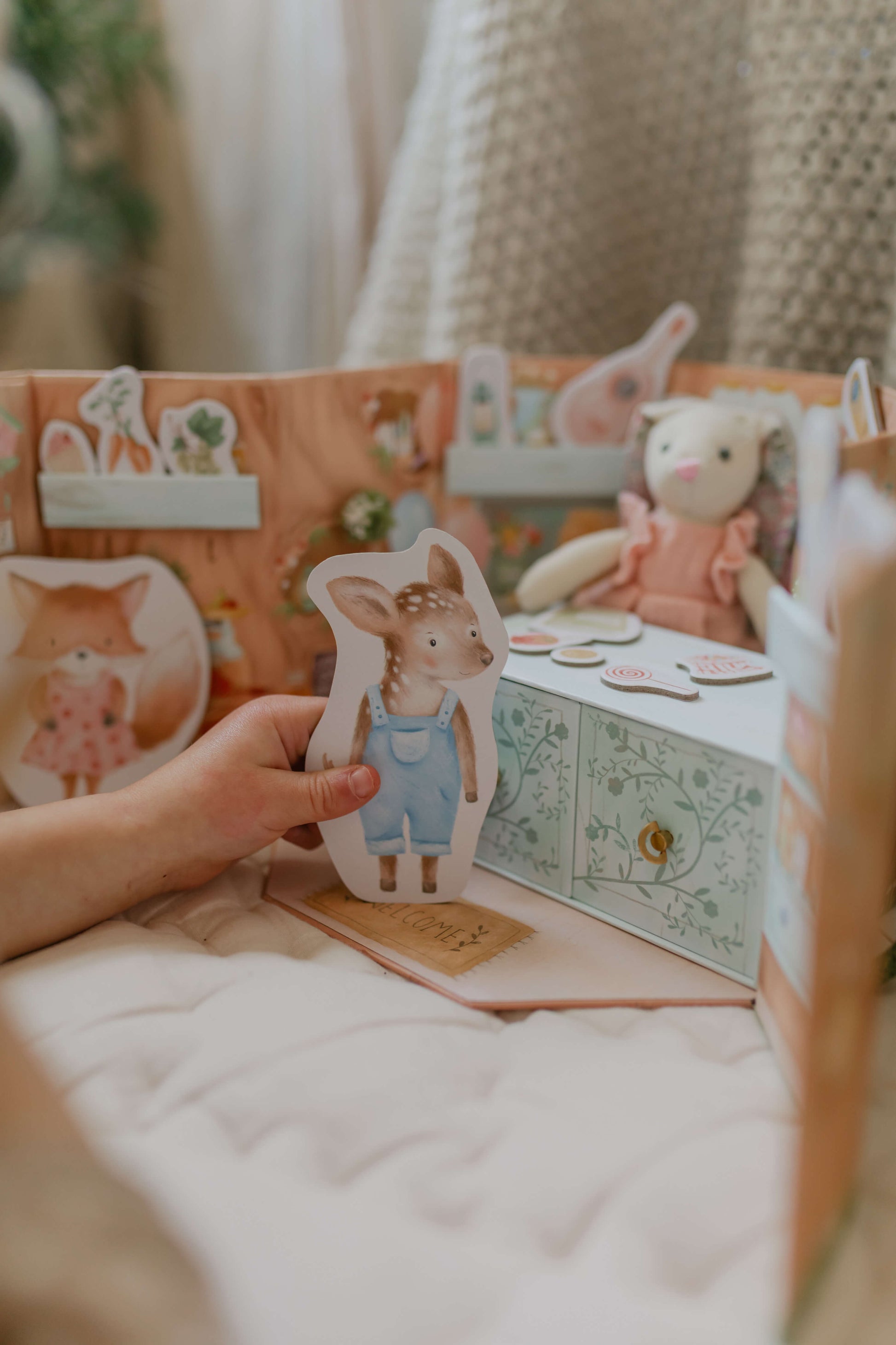 Child holding Dora Deer character and inside the Woodland Wonders children's playset.