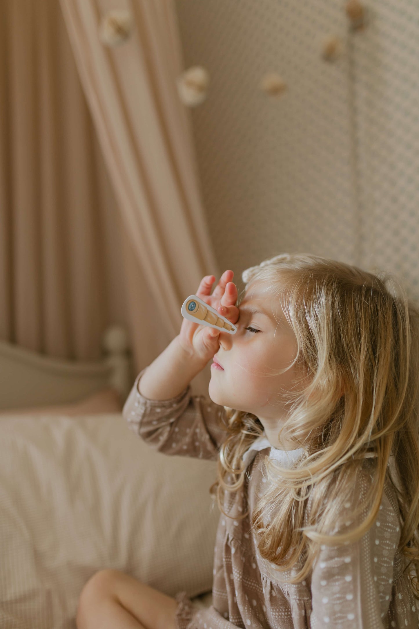 Child holding a toy telescope in a cosy indoor setting.